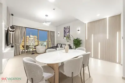 a dining room with a white table and chairs at SML Vacation Homes - Sky High Apartments with Burj Khalifa and Dubai Fountain Views at Grande Signature, Downtown Dubai in Dubai