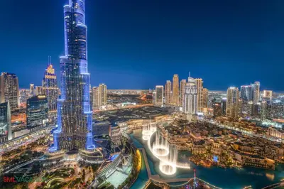a city skyline at night with a tall skyscraper at SML Vacation Homes - Sky High Apartments with Burj Khalifa and Dubai Fountain Views at Grande Signature, Downtown Dubai in Dubai
