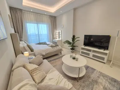a living room with a couch and a tv at Studio in Hera towers, Dubai sports city in Dubai