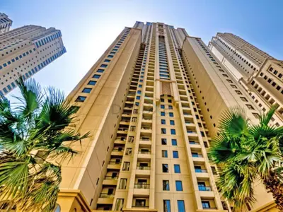 a tall building with palm trees in front of it at Sea-Facing 1BR with Ain Dubai View Close to Marina Beach, Rimal 3, Jumeirah Beach Residence by Deluxe Holiday Homes in Dubai