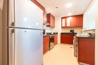a kitchen with red cabinets and a refrigerator at Sea-Facing 1BR with Ain Dubai View Close to Marina Beach, Rimal 3, Jumeirah Beach Residence by Deluxe Holiday Homes in Dubai