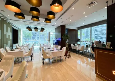 a restaurant with white tables and chairs and large windows at Nice 2 Bedroom Apartment! 5 Minute walk to Dubai Mall! Burj Khalifa View! in Dubai