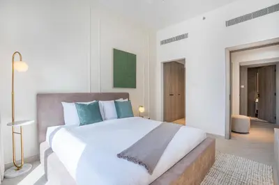 a bedroom with a large white bed with blue pillows at Stylish 1BR Retreat in JVC Modern & Cozy Stay in Dubai