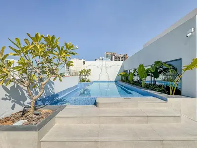 a swimming pool with stairs leading to a building at Stylish Studio Retreat Modern Stay in JVC in Dubai