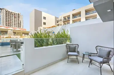 two chairs and a table on a balcony with buildings at Stylish Studio Retreat Modern Stay in JVC in Dubai