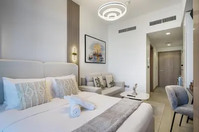 a bedroom with a large white bed and a living room at Luxury Meydan Studio Near Dubai Mall & Downtown in Dubai