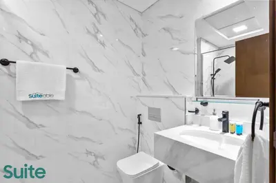 a white bathroom with a sink and a mirror at Luxe Interior Studio in Pantheon Elysee 3 in JVC in Dubai