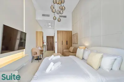 a white bedroom with a large bed and a tv at Luxe Interior Studio in Pantheon Elysee 3 in JVC in Dubai