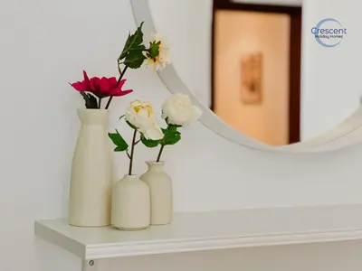 three white vases with flowers on a shelf in front of a mirror at Relaxing Beach Escape in JBR in Dubai