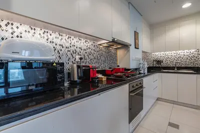 a kitchen with white cabinets and a black counter top at Near Dubai Mall - Pool Access - Sun Set View - KingBed in Dubai