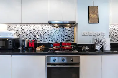 a kitchen with white cabinets and a stove top oven at Near Dubai Mall - Pool Access - Sun Set View - KingBed in Dubai