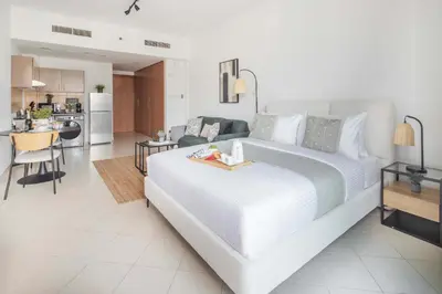 a bedroom with a large white bed and a kitchen at Frank Porter - Lago Vista in Dubai