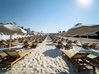 a row of chairs and umbrellas on a beach at Palm Jumeirah Beachfront apartment with Amazing Infinity Pool and private beach in Dubai