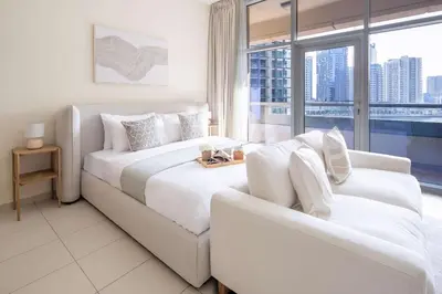 a white bedroom with a large bed and a couch at Frank Porter - Bay Square in Dubai
