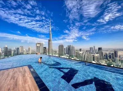 a man in a infinity pool on the top of a building at Stylish 2BR Apt in 5 Star Hotel with Burj Khalifa Views in Dubai