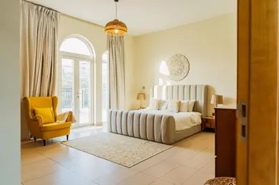 a bedroom with a large bed and a yellow chair at Stunning 4BR Jumeira Park Villa With Pool and Jacuzzi in Dubai
