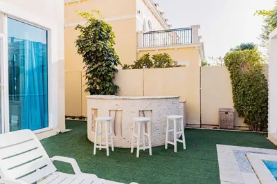a patio with chairs and a bar on a building at Stunning 4BR Jumeira Park Villa With Pool and Jacuzzi in Dubai