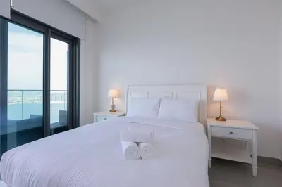 a bedroom with a white bed with two towels on it at Luxury 2BR Apt with Pool, Gym & Sea Views in Dubai