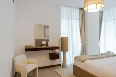 a bedroom with a bed and a chair and a mirror at FAM Living - 3 bedroom and Maids Room Retreat Overlooking Dubai Canal in Dubai