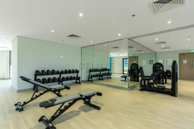 a gym with a mirror and rows of exercise equipment at Community View Studio with Balcony, Azizi Riviera 24, Al Merkadh by Deluxe Holiday Homes in Dubai
