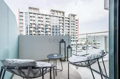 a balcony with chairs and a table and a building at Community View Studio with Balcony, Azizi Riviera 24, Al Merkadh by Deluxe Holiday Homes in Dubai