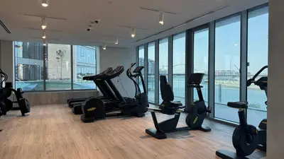 a gym with treadmills and exercise bikes in a room with windows at Magnificent - New 1BR in Canal Front Residences in Dubai