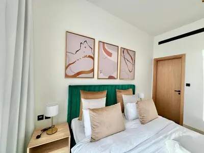 a bedroom with a bed with a green headboard at Stylish 1br With Garden View In Jvc in Dubai