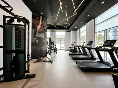 a gym with a bunch of treadmills and machines at Silkhaus Cozy Studio at Madison in Barsha Heights in Dubai