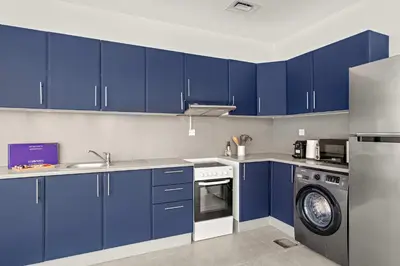 a kitchen with blue cabinets and a washing machine at Silkhaus Large Studio in Madison near Barsha Heights in Dubai