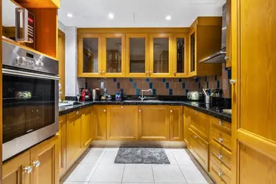 a kitchen with wooden cabinets and black counter tops at Stylish 2-Bedroom in the Heart of OldTown Dubai in Dubai