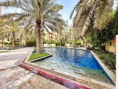 a swimming pool with a palm tree in a courtyard at Stylish 2-Bedroom in the Heart of OldTown Dubai in Dubai