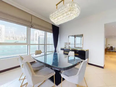 a dining room with a glass table and white chairs at Spacious Duplex 4BR with Maids Room in Dubai