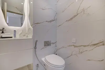 a white bathroom with a toilet and a marble wall at Luxurious Apartment And Amazing Dubai Marina View in Dubai