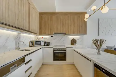 a kitchen with white counter tops and wooden cabinets at Luxurious Apartment And Amazing Dubai Marina View in Dubai