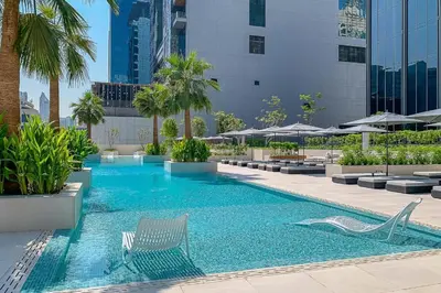 a swimming pool with chairs and umbrellas in a building at Luxury 2BHK Plus Maid's Room The Sterling West Near Dubai Mall in Dubai