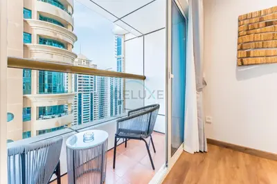 a balcony with a chair and a table at Upgraded 2BR with Partial Sea and City Views Near the Beach, Elite Residence, Dubai Marina by Deluxe Holiday Homes in Dubai