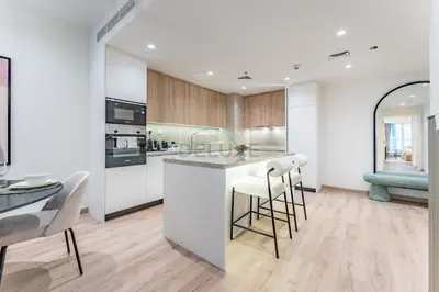 a kitchen with white cabinets and a counter with bar stools at Renovated 1BR with Partial Sea and City Views Close to the Beach, Elite Residence, Dubai Marina by Deluxe Holiday Homes in Dubai