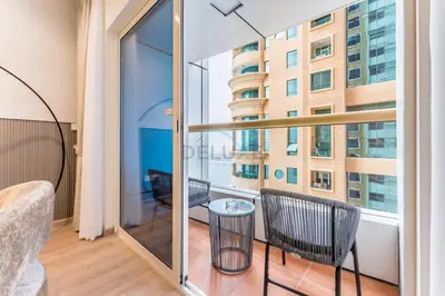 a room with a balcony with a table and chairs at Renovated 1BR with Partial Sea and City Views Close to the Beach, Elite Residence, Dubai Marina by Deluxe Holiday Homes in Dubai