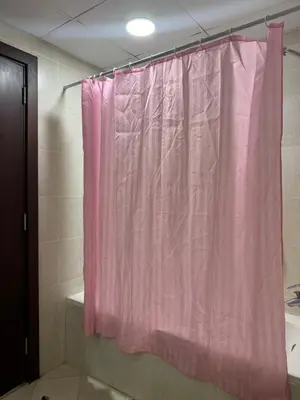 a pink shower curtain in a bathroom with a tub at Cozy 1Bed Sports city in Dubai