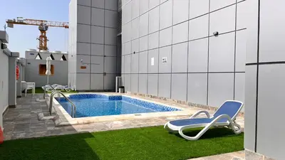 a swimming pool with a lounge chair and a swimming pool at Cozy 1Bed Sports city in Dubai