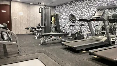 a gym with several tread machines in a room at Cozy 1Bed Sports city in Dubai