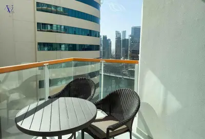 a table and chairs on a balcony with a view of a city at Luxurious 2-Bedroom Haven in Dubai