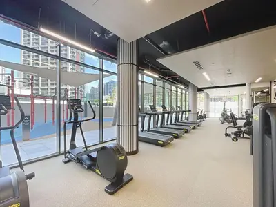 a gym with a row of treadmills and ellipticals at Peninsula - Modern Two Bedroom in Business Bay in Dubai