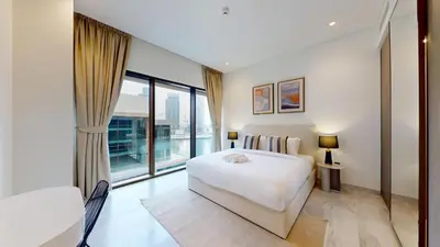a bedroom with a white bed and a large window at Peninsula - Modern Two Bedroom in Business Bay in Dubai