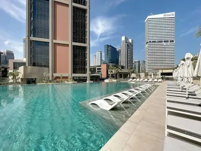a large swimming pool with lounge chairs and buildings at Peninsula - Modern Two Bedroom in Business Bay in Dubai