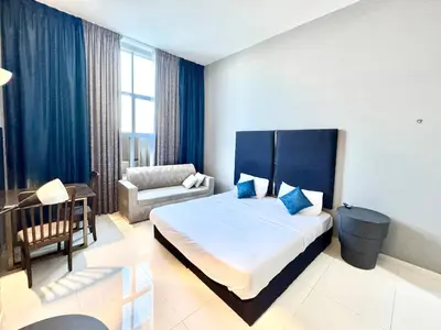 a bedroom with a bed and a chair and a desk at Al Manara Classic Luxe Studio in Dubai