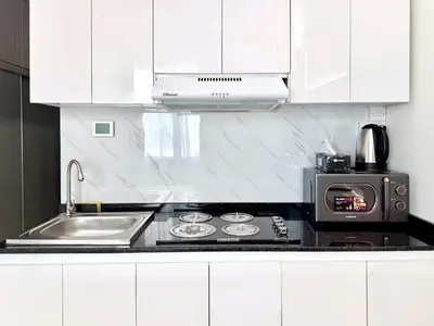 a kitchen with white cabinets and a stove and a microwave at Al Manara Premium Cozy Studio in Dubai