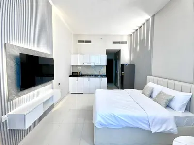 a white bedroom with a bed and a kitchen at Al Manara Premium Lux Studio in Dubai