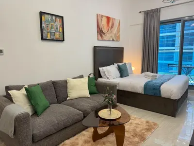 a living room with a couch and a bed at Chic Studio with Balcony a mins drive to Downtown in Dubai