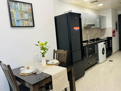 a kitchen with a table and a dining room at Chic Studio with Balcony a mins drive to Downtown in Dubai